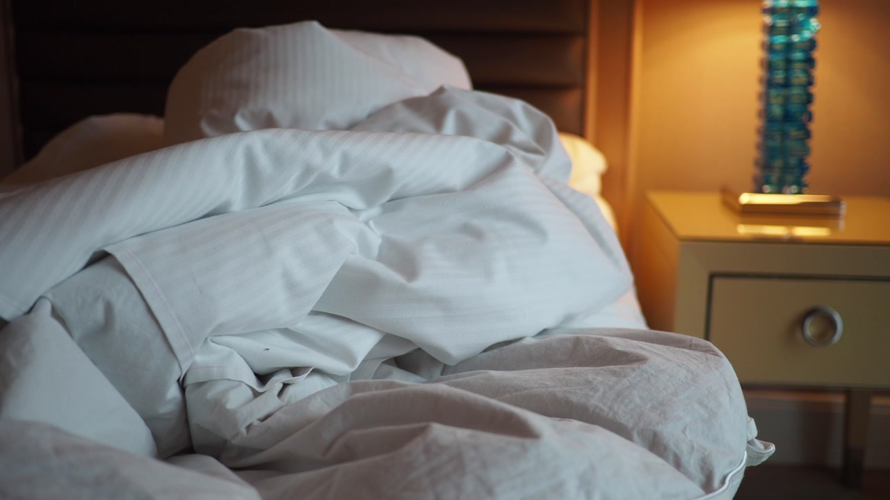 Cozy Unmade Bed with Rumpled White Sheets and Pillows