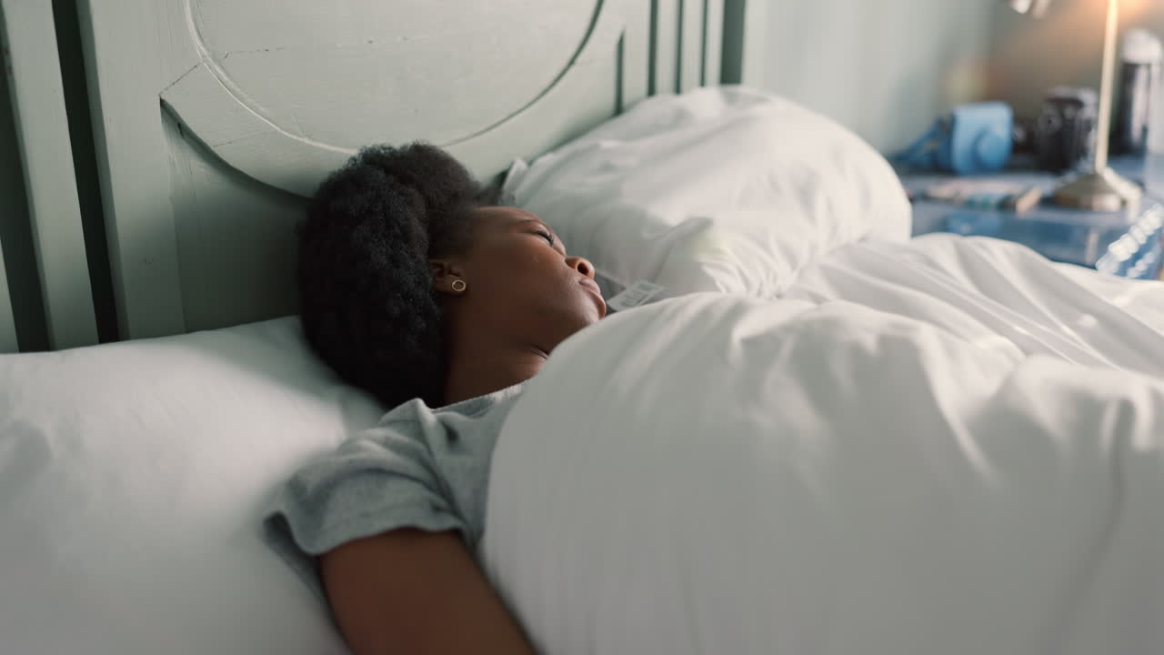 Kvinde sover i seng med vækkeur