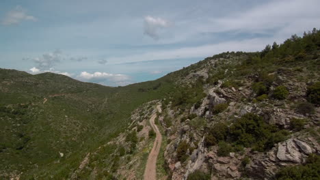 Fly-above-Penteli's-winding-gravel-road-with-a-drone