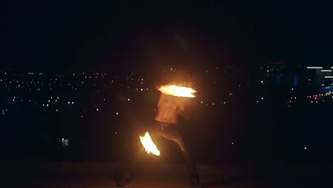 Young-blond-male-spins-two-burning-pois-on-black-night-city-background-Slow-motion-shot