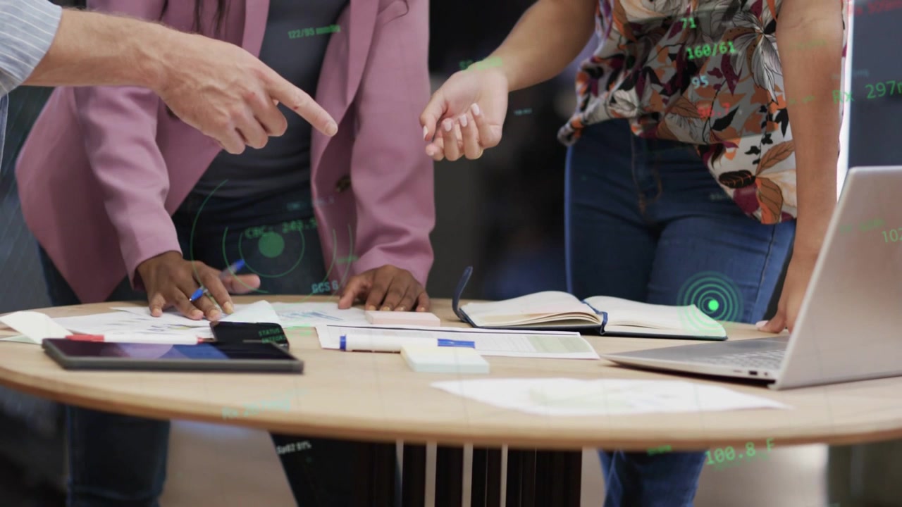 Team aziendale chinato su un tavolo, un uomo che indica, una donna che scrive, con HUD che mostra metriche per le decisioni.