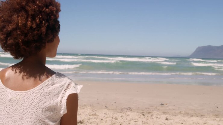 Rear view of young African american woman relaxing on beach in the sunshine 4k