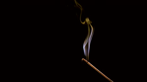 an incense stick burns and smokes.