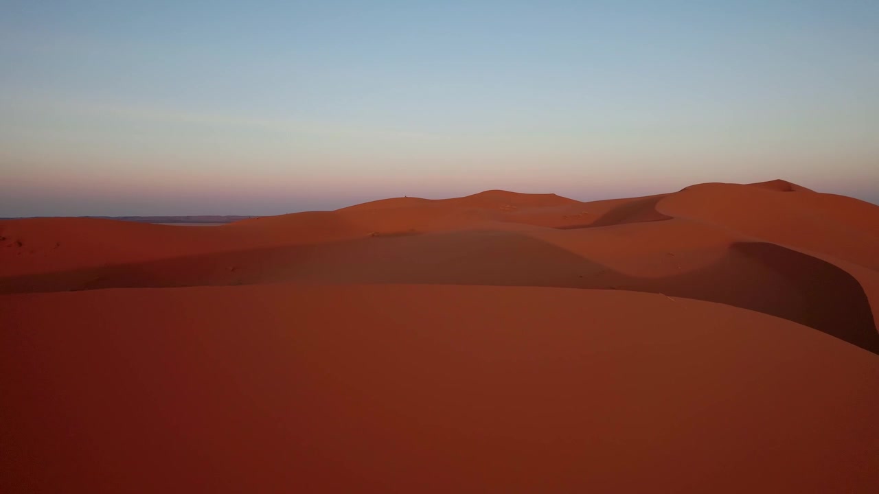 Il mare di dune di Erg Chebbi, vicino a Merzouga, Marocco, rivela ampie texture sabbiose e formazioni sahariane ondulate illuminate dalla calda luce dell'alba, ripresa in volo in avanti con drone.