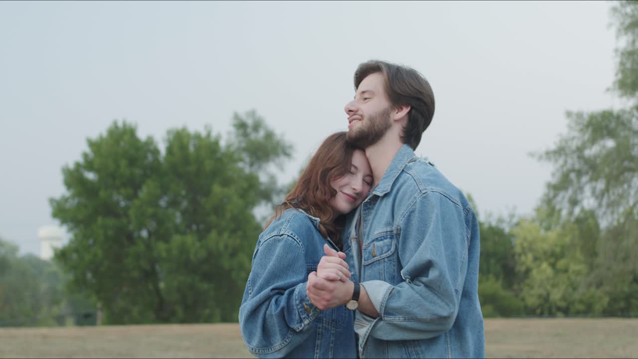 Couple wearing denim dance together in a park at sunset outdoors