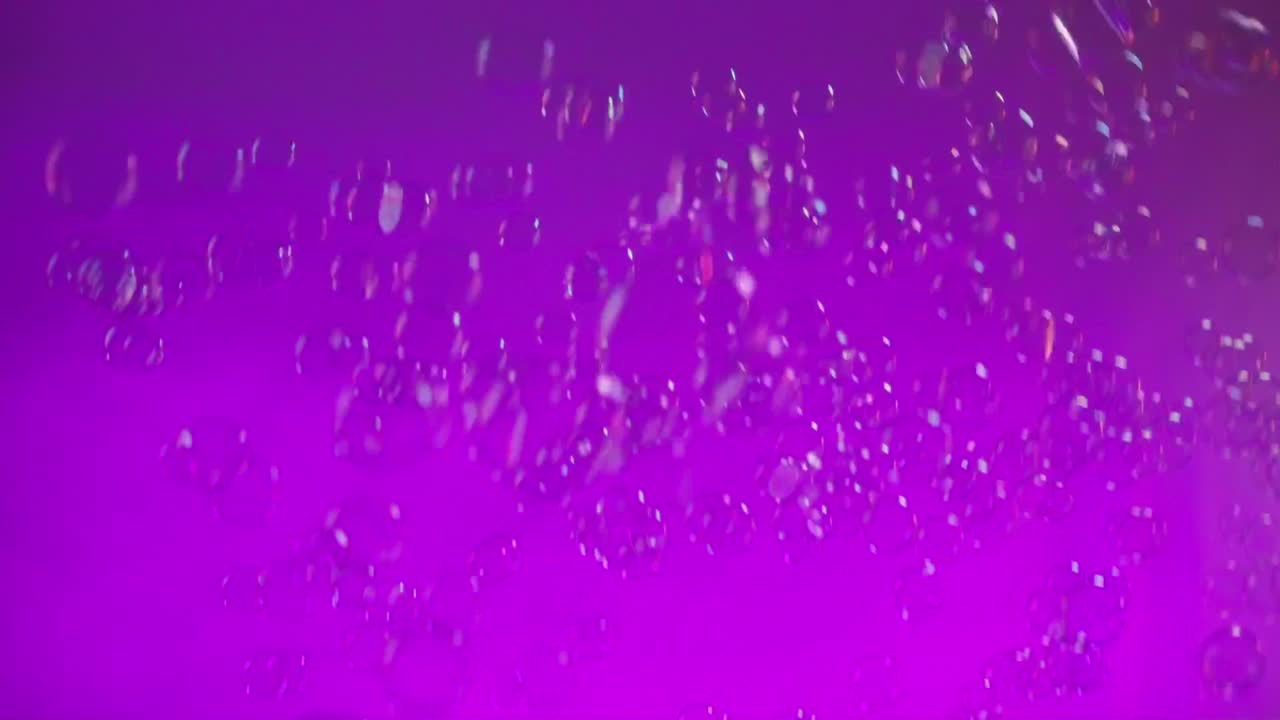 Floating soft bubbles shimmer and dance through vibrant purple stage lighting