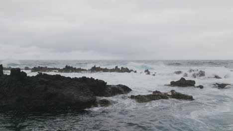 Olas-Frías-Del-Océano-Golpeando-Las-Rocas-En-Cámara-Lenta-Con-Drones-Aéreos