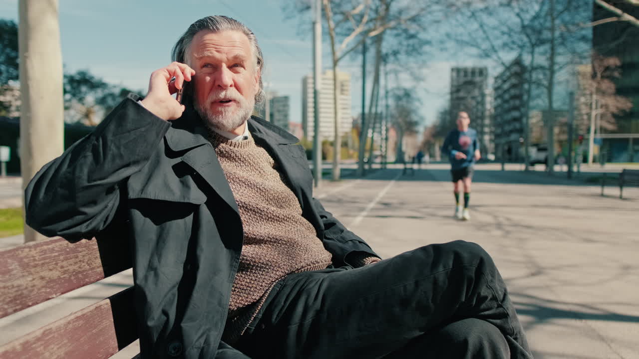 Elderly Man Talking On Phone In City Park