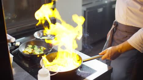 chef flambeing fish in frying pan