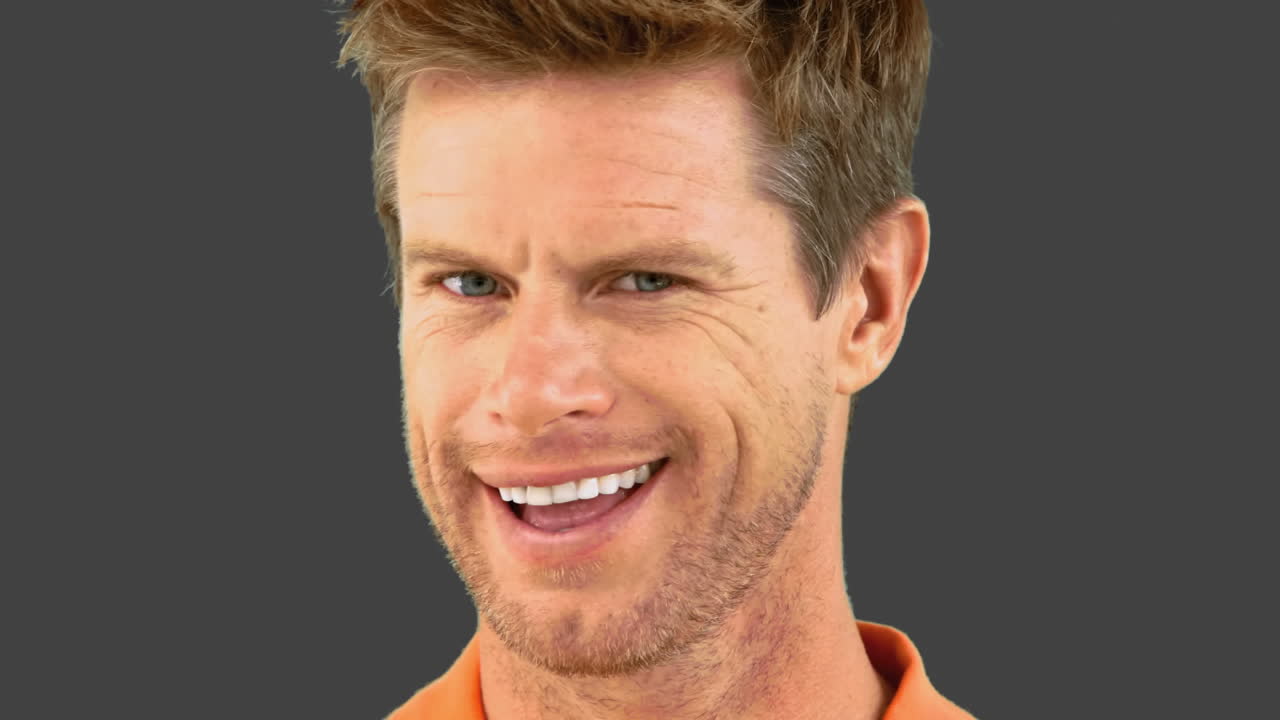 Cheerful man winking an eye on grey screen