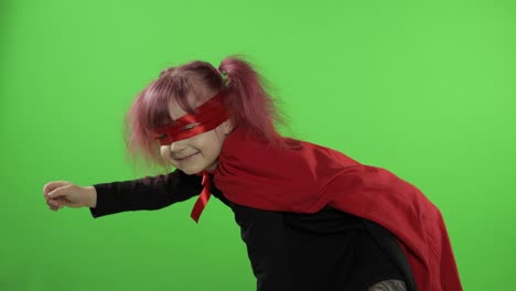 funny child girl in costume and mask plays super hero. national superhero day