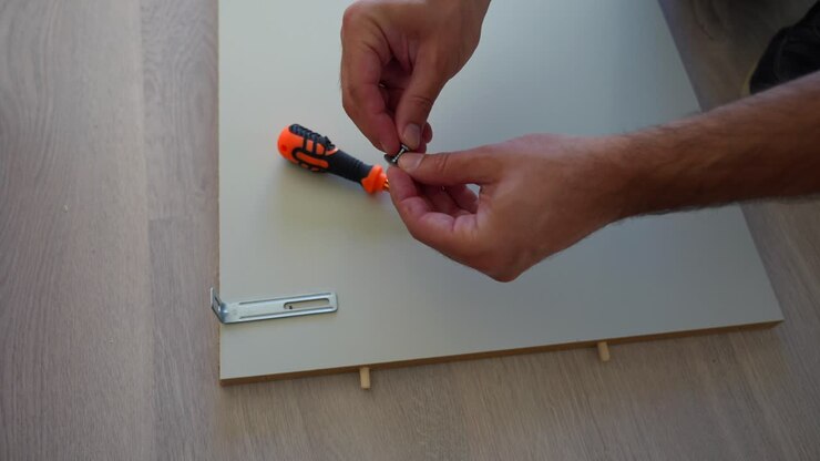 Close up of man hands assembling furniture at home on wooden floor, high view