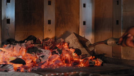 raking coals into a wood fired grill