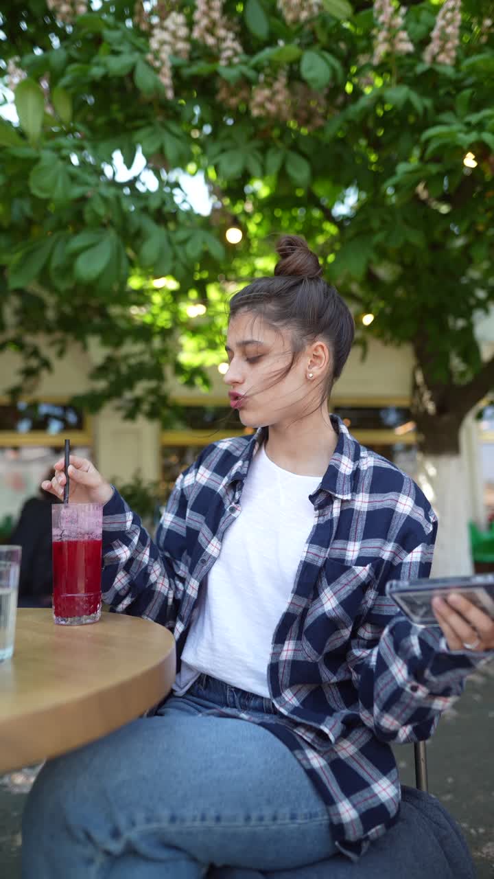 una mujer joven disfrutando de una bebida y usando su teléfono en un café
