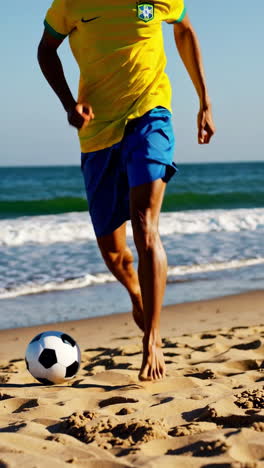 person playing soccer on a sunny beach in a brazil jersey