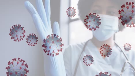 Animation-of-covid-19-cells-with-female-doctor-wearing-mask-putting-on-gloves