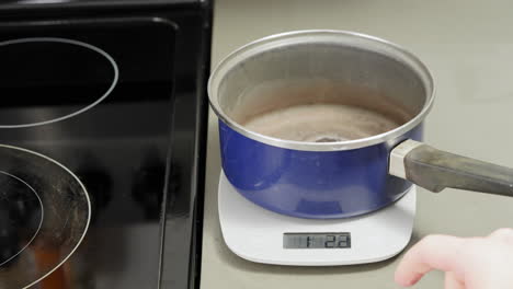 using a digital scale to zero out a sauce pan so precise measurements can be made