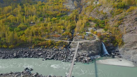 stunning aerial view of a bridge over the indus river in pakistan, surrounded by autumn foliage and rocky terrain, showcasing natural beauty and engineering