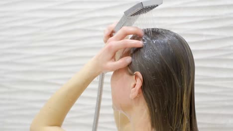 young woman washing hair in shower at home, back view. healthy lifestyle. beauty spa concept.