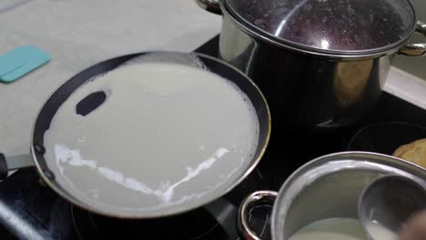 The-process-of-cooking-homemade-pancakes.-Woman-pours-pancake-dough-on-pan