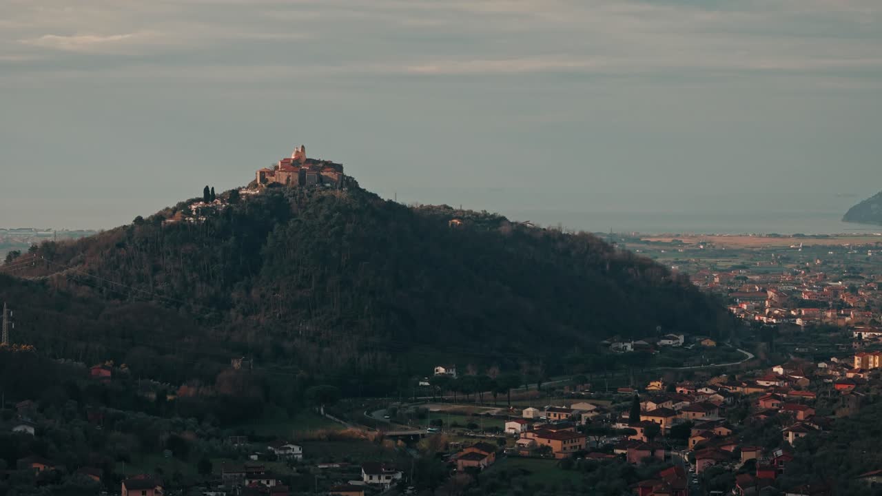 Aerial ascent approaching Nicola, Italy, rolling hills and rustic homes under golden afternoon light, establishing overview