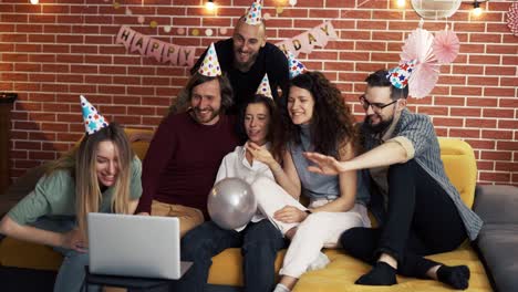 group of people at home celebrating birthday wearing party hats, gasping in surprise, having video call