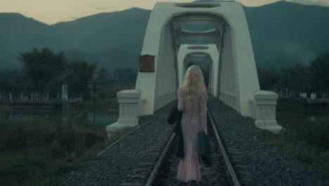 woman walking across a bridge on train tracks