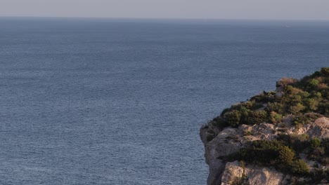 aerial shot of the edge of a cliff with the ocean in the background on the island of sardinia in the mediterranean sea of italy at sunset medium shot