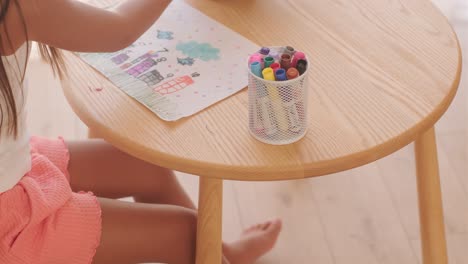 child drawing at a table with markers