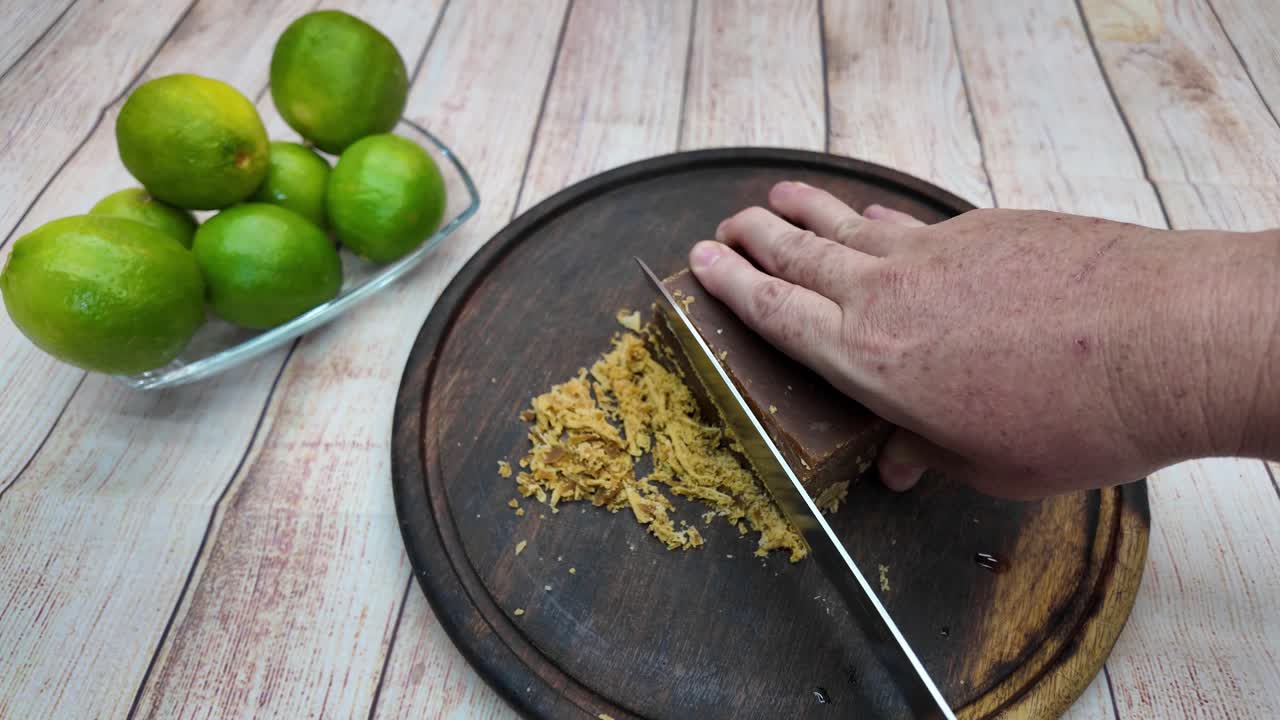 Cutting panela block for cooking on wooden board in bright kitchen setup