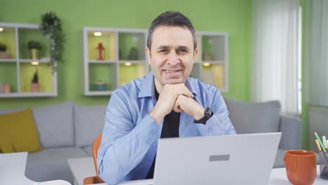 hombre trabajador de oficina en casa mirando a la cámara y sonriendo.