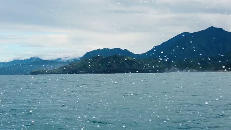 HD-120fps-Hawaii-Kauai-Boating-on-the-ocean-floating-right-to-left-with-green-hills-and-mountains-in-cloudy-distance-with-boat-spray-in-foreground