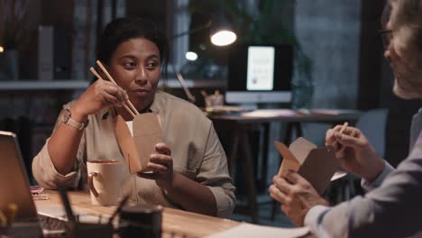 two coworkers eat food and talk while taking a break 1