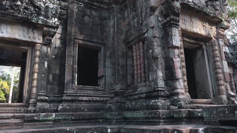 close exterior panning shot of the doors and windows with carved and decorated frames of ancient temple structure near angkor wat