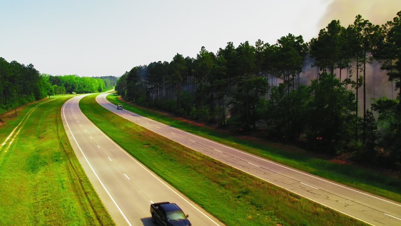 Vehicles Driving Along Rural Highway Next to Forest Fire Smoke in America