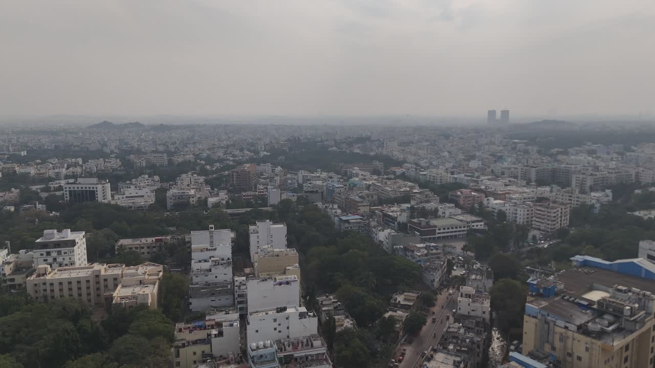 Scatto aereo ad alta quota del paesaggio urbano di Hyderabad con complessi residenziali, strutture commerciali e vegetazione circostante