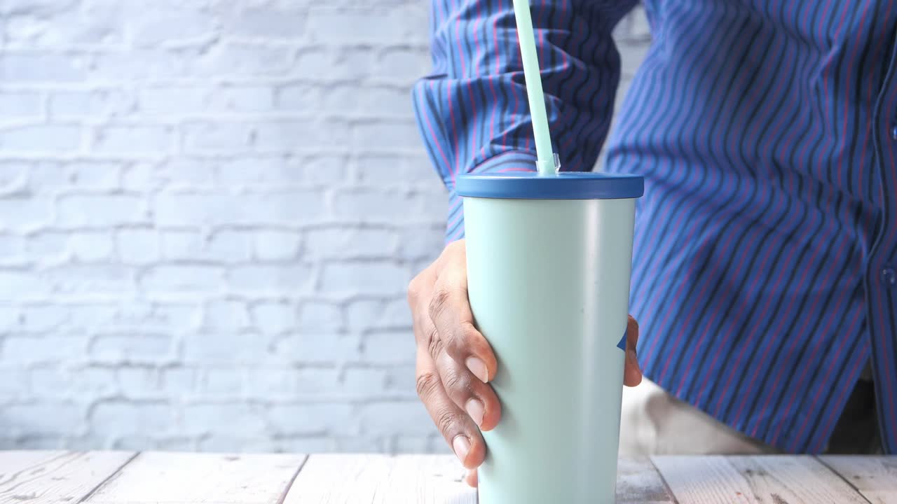 persona sosteniendo un vaso de color menta claro con una paja