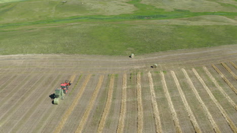 Landwirtschaftlicher-Traktor,-Der-Heu-Auf-Dem-Weiten-Feld-In-Saskatchewan,-Kanada-Ballt---Luftdrohne