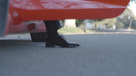 cinematic close up shot of man stepping out of red corvette