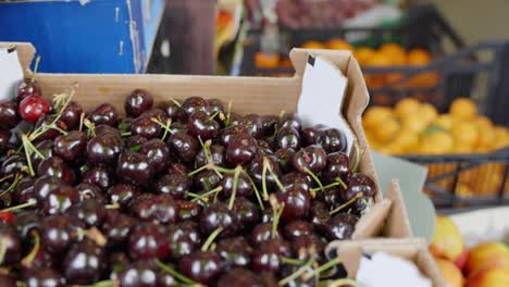 Fresh-fruits-at-local-market,-oranges,-red-cherries,-yellow-plums,-closeup