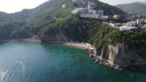 Vista-Aérea-De-La-Playa-De-Arena-Escondida-De-Mogren-Bajo-El-Acantilado-En-Budva,-Montenegro