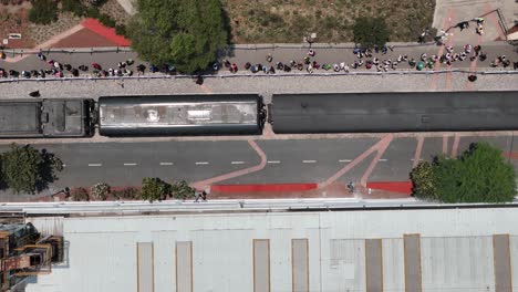 aerial top-down view of a train with a crowd of spectators in an urban setting
