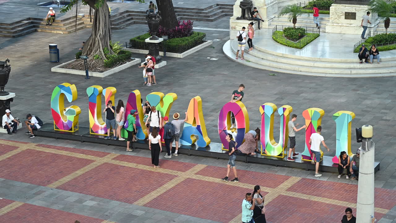 Tourist walking by and taking pictures at Guayaquil letters in Malecon Simon Bolivar in downtown Guayaquil. Many