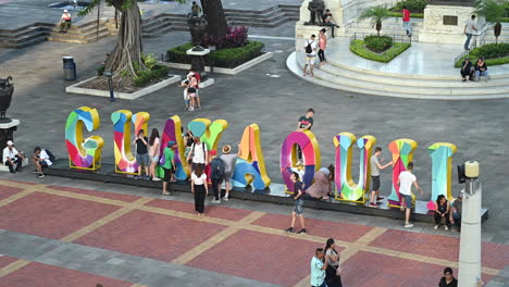 tourist walking by and taking pictures at guayaquil letters in malecon simon bolivar in downtown guayaquil. many