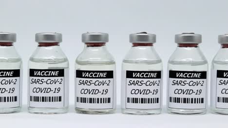 row of covid vaccine glass vials isolated in white background - sars-cov-2 vaccination concept - slider right, studio shot