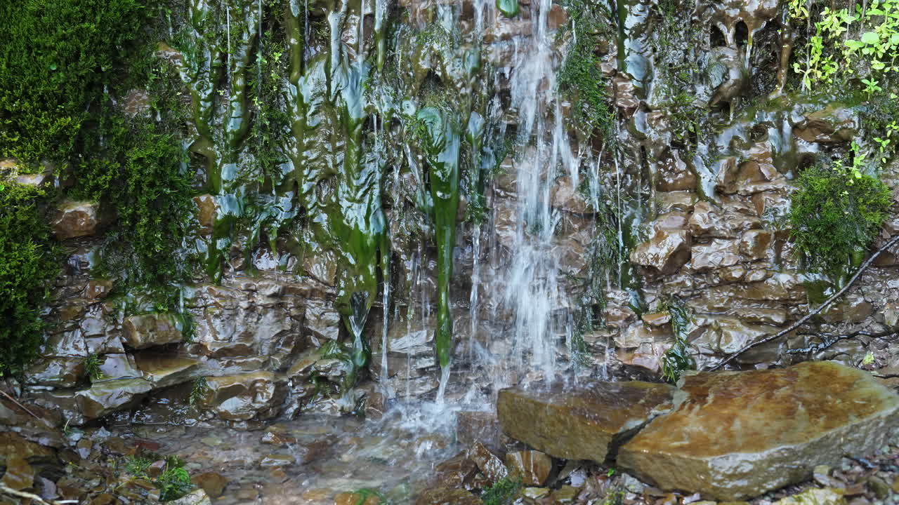 pequeña cascada que cae en cascada sobre rocas y musgo