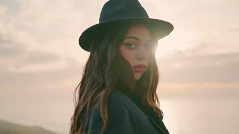 relaxed girl traveler posing in front beautiful sunset wearing hat close up.