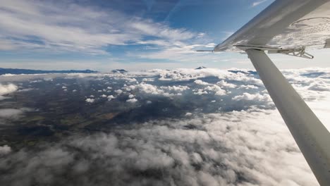 pov small airplane flying over wilderness with mountains and clouds, bush aviation