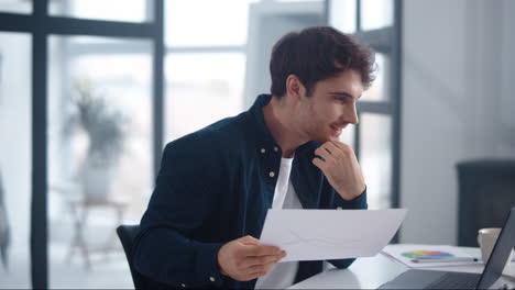 hombre de negocios sonriente leyendo gráficos investigación en la oficina de casa