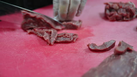 4k: chef cutting raw meat on a cutting board in a professional kitchen